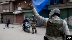 Tentara paramiliter India memerintahkan para komuter untuk berputar arah karena jalanan ditutup karena alasan keamanan di pusat kota Srinagar, Kashmir yang dikuasai India, 1 Maret 2019.