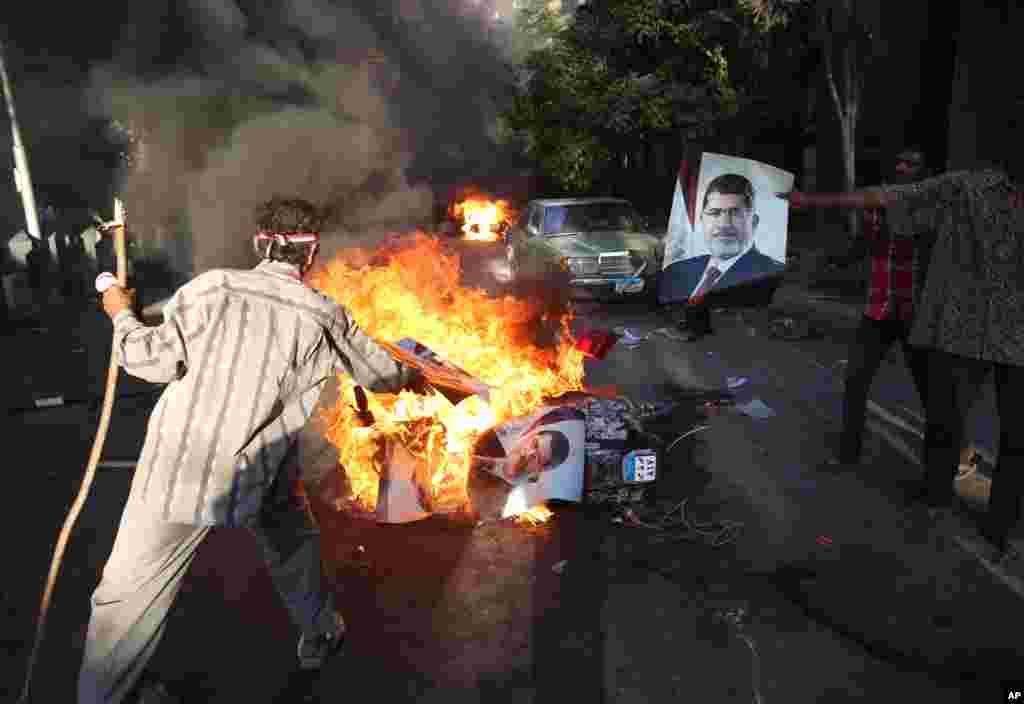 Opponents of ousted President Mohammed Morsi burn posters bearing his picture during clashes against Morsi supporters, in Cairo, Egypt, July 22, 2013.