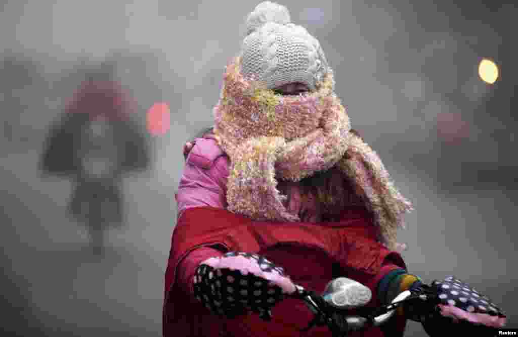 Seorang perempuan naik sepeda di jalanan berkabut karena cuaca sangat dingin di Haozhou, provinsi Anhui, Tiongkok. 