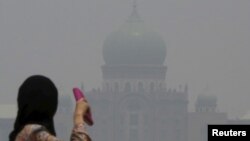 A woman looks toward the prime minister's office, which is shrouded in haze from Indonesian fires, in Putrajaya, Malaysia, Oct. 6, 2015. 