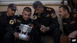 FILE - Iraqi special forces Lt. General Abdul-Wahab al-Saadi, center, looks at a live video feed from a drone flying over Islamic State militant-held territory as they advance their position in Mosul, Iraq, Nov. 18, 2016.