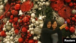 Two women photograph themselves in front of a Christmas tree in a shopping mall in Jakarta.