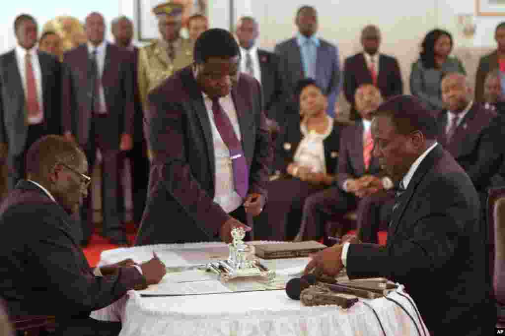Emmerson Mnangagwa, à droite, signe des papiers au cours d&#39;une cérémonie de prestation de serment pour son poste de vice-président devant le président zimbabwéen Robert Mugabe, à gauche, au State House à Harare, vendredi 12 décembre 2014