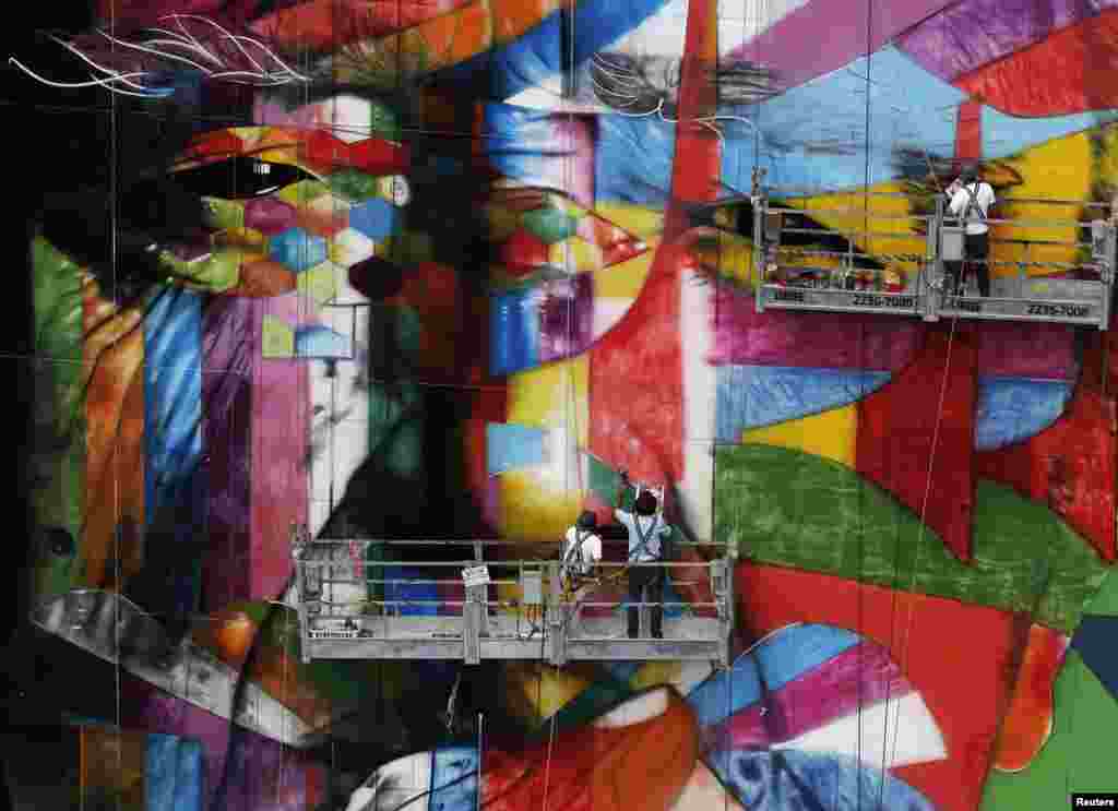 Brazilian graffiti artist Eduardo Kobra (center) puts the final touches to his 56-meter tall artwork in tribute to architect Oscar Niemeyer, one of the 20th century&#39;s most influential modernist architects, at the financial center on Sao Paulo&#39;s Avenida Paulista, January 22, 2013. Niemeyer died in December 2012, aged 104.