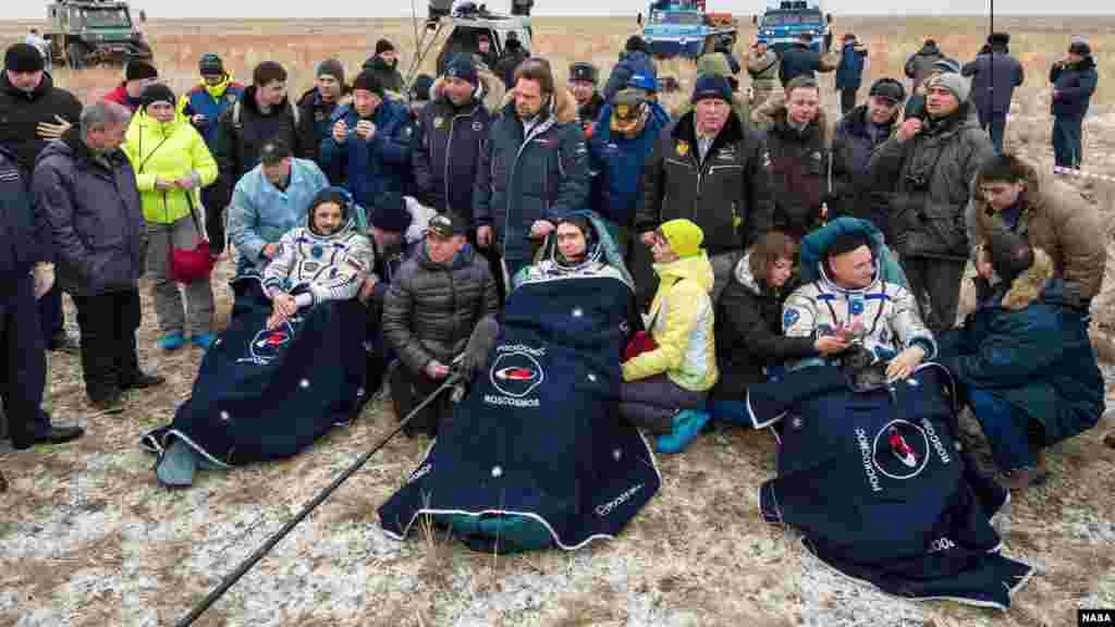 Kosmonot Rusia Mikhail Kornienko (kiri), kosmonot Sergey Volkov, dan astronot AS Scott Kelly (kanan), beristiirahat di kursinya sesaat setelah mendarat dengan pesawat Soyuz TMA-18M di Dzhezkazgan, Kazakhstan (2/3).