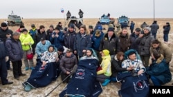 FILE - Russian cosmonauts Mikhail Kornienko, left, Sergey Volkov of Roscosmos, center, and Expedition 46 Commander Scott Kelly of NASA, rest in chairs outside of the Soyuz TMA-18M spacecraft just minutes after they landed in a remote area near the town of Zhezka