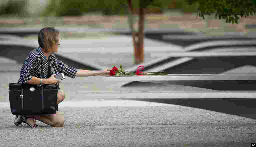 A woman reaches out to touch a rose on one of the benches of the Pentagon Memorial at the Pentagon, Sept. 11, 2014.