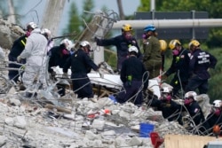 In this Monday, July 5, 2021, file photo, rescue workers move a stretcher containing recovered remains at the site of the collapsed Champlain Towers South condo building, in Surfside, Fla. (AP Photo/Lynne Sladky, File)