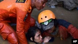 Rescuers evacuate an earthquake survivor by a damaged house following earthquakes and tsunami in Palu, Central Sulawesi, Indonesia, Sunday, Sept. 30, 2018.