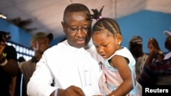 Julius Maada Bio, the presidential candidate for the Sierra Leone People's Party (SLPP), carries his daughter as he casts his vote during a presidential run-off in Freetown, Sierra Leone, March 31, 2018. 