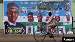 A cyclist rides past a campaign poster for President Muhammadu Buhari days before the presidential election, in Kano, Nigeria, Feb. 17, 2019.