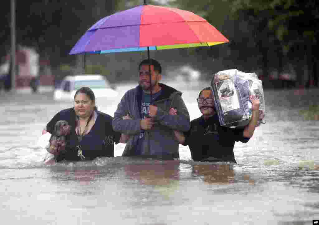 Felix Yanez, au centre, aide Lucy Olvio et Judy à marcher dans l'eau lors des inondations à Houston, Texas, 18 avril 2016.