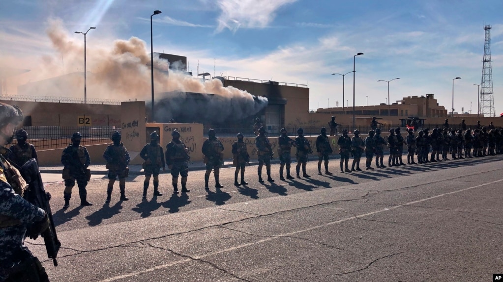 Iraqi security forces stand guard in front of the U.S. embassy in Baghdad, Iraq, Wednesday, Jan. 1, 2020. 