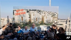 FILE - Israeli Minister of Housing and Construction Uri Ariel, center, speaks to journalists during ceremony marking resumption of construction in east Jerusalem.
