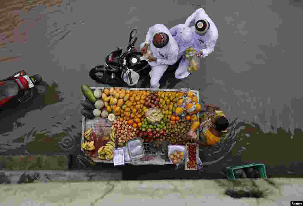 People buy fruits from a street hawker on a waterlogged road after heavy rain in the western Indian city of Ahmedabad, India. The monsoon rains were 15 percent below average in the past week, against 41 percent below average rainfall in the previous week.