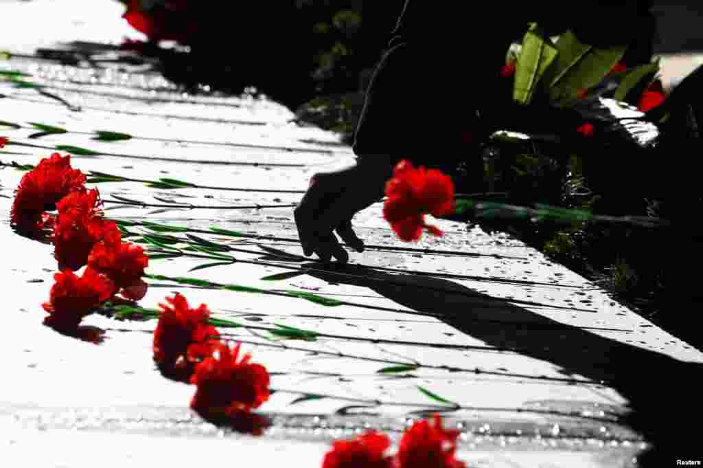 A man lays flowers at the World War Two memorial in the former village of Khatyn, Belarus. Nazi troops killed 149 villagers on March 22, 1943, most of them children and women, and burned down their houses. The village was never restored again, according to historians.