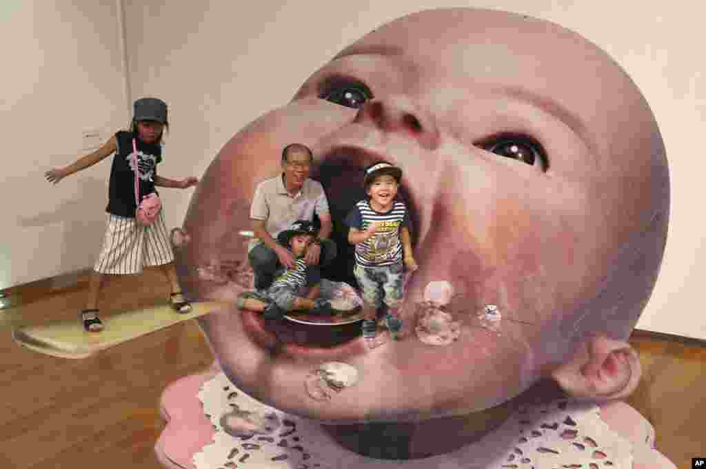 Para pengunjung berpose dengan latar belakang lukisan 3 Dimensi karya seniman Masashi Hattori pada pameran karya seni 3 Dimensi di Tokyo, Jepang.