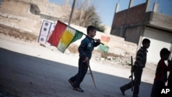 FILE - A boy carries a Kurdish flag on a street in Ras al-Ayn, Syria, Feb. 26, 2013. Taking advantage of the chaos of the civil war, Syria’s Kurdish minority has carved out a once unthinkable independence in their areas, even going public with their language and culture.