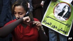 An Egyptian woman cuts her hair during a demonstration in Tahrir Square, Cairo, Egypt, Tuesday, Dec. 25, 2012.