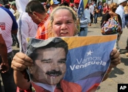 A supporter of Venezuela's President Nicolas Maduro holds a poster of him during a rally in Urena, Venezuela, Monday, Feb. 11, 2019.