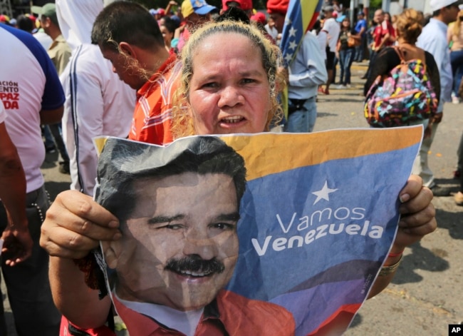 A supporter of Venezuela's President Nicolas Maduro holds a poster of him during a rally in Urena, Venezuela, Monday, Feb. 11, 2019.