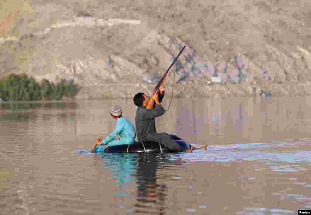 아프가니스탄 라그만주의 강에서 남성이 날고 있는 청둥오리를 향해 총을 겨누고 있다.