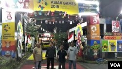 Pengurus RT 23 RW 07 Sekardangan, Sidoarjo berpose dengan latar belakang gapura tematik Asian Games 2018 dan bendera-bendera negara peserta. (Foto: Petrus Riski/VOA)
