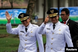 FILE - Jakarta Governor Anies Baswedan, right, and his deputy Sandiaga Uno wave to reporters before a swearing-in at the Presidential Palace in Jakarta, Indonesia, Oct. 16, 2017.