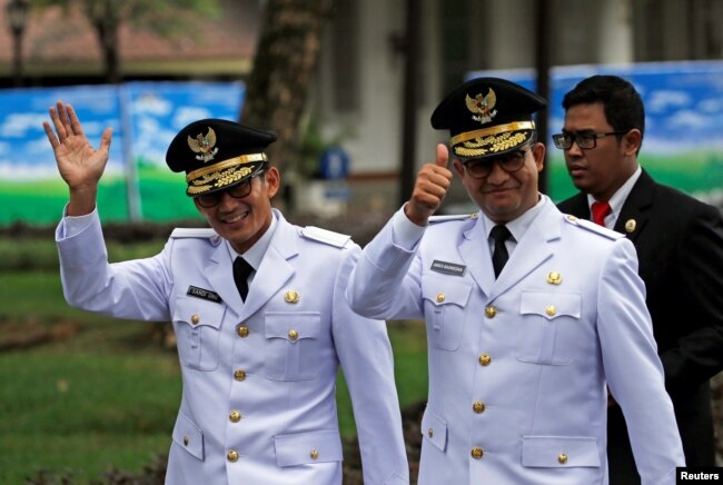 Gubernur Jakarta Anies Baswedan, kanan, dan wakilnya yang saat itu masih dijabat Sandiaga Uno melambai kepada wartawan sebelum pengambilan sumpah di Istana Kepresidenan di Jakarta, 16 Oktober 2017. (Foto: Reuters)
