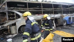 Firefighters carry a victim in a body bag as they work at the accident site after a collision between a bus and a methanol-loaded tanker occurred in Yan'an, Shaanxi province, August 26, 2012. 