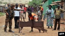 FILE - A French soldier of the Sangaris military operation orders a man to give back the items he looted in the 5th district of Bangui, Feb. 9, 2014. 