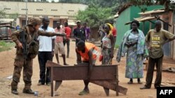 Un soldat français de l'opération militaire de Sangaris ordonne à un homme de rendre les objets qu'il a pillés dans le 5ème arrondissement de Bangui, 9 février 2014.