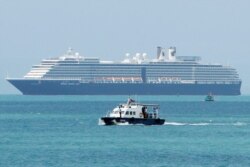 A speed boat, foreground, transports samples from some passengers who have reported stomachaches or fever, in the Westerdam, seen in the background, off Sihanoukville, Cambodia, Feb. 13, 2020.