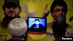 A Shi'ite sheikh watches Lebanon's Hezbollah leader Sayyed Hassan Nasrallah speaking on television in Nabatieh in southern Lebanon, Aug. 4, 2017.