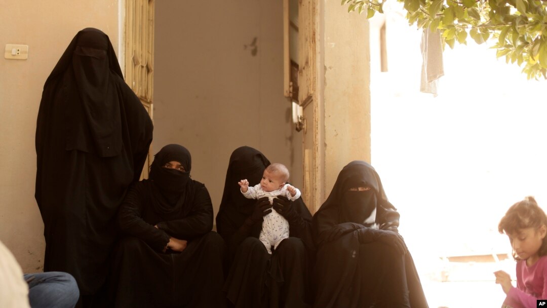 FILE - Women who recently returned from the Al-Hol camp, which holds families of Islamic State members, gather in the courtyard of their home in Raqqa, Syria, during an interview, Sept. 7, 2019.