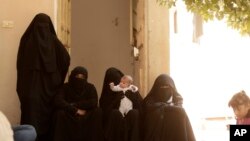 FILE - Women who recently returned from the Al-Hol camp, which holds families of Islamic State members, gather in the courtyard of their home in Raqqa, Syria, during an interview, Sept. 7, 2019.