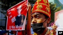 Demonstrators in traditional costumes display a picture of Myanmar president Win Myint during a protest march against the military coup in Mandalay, Myanmar, Feb. 11, 2021.