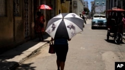 Una persona se protege del calor bajo una sombrilla en una calle de La Habana, Cuba, el 5 de julio de 2023. 