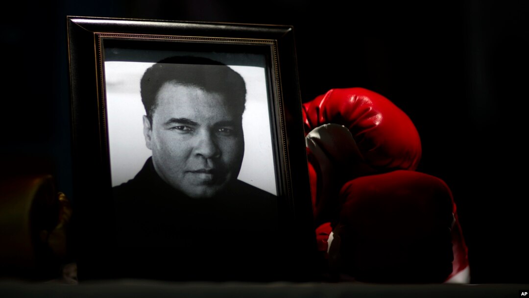 FILE - A portrait of Muhammad Ali is displayed next to a pair of boxing gloves at the I Am Ali Festival in Louisville, Kentucky, June 8, 2016.