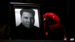 ARSIP – Sebuah potret Muhammad Ali diperagakan di saming sepasang sarung tinju pada Festival I Am Ali di Louisville, Kentucky, 8 Juni 2016 (foto: AP Photo/David Goldman)