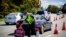 FILE - A Queensland police officer moves a stop sign at a vehicle checkpoint on the Pacific Highway on the Queensland - New South Wales border, in Brisbane on April 15, 2020. 