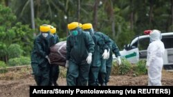 Petugas Pemkot mengenakan alat pelindung diri memakamkan korban COVID-19 di area pemakaman yang disediakan pemerintah di Pulau Sangihe, Sulawesi Utara, 17 April 2020. (Foto: Antara/Stenly Pontolawokang via REUTERS)