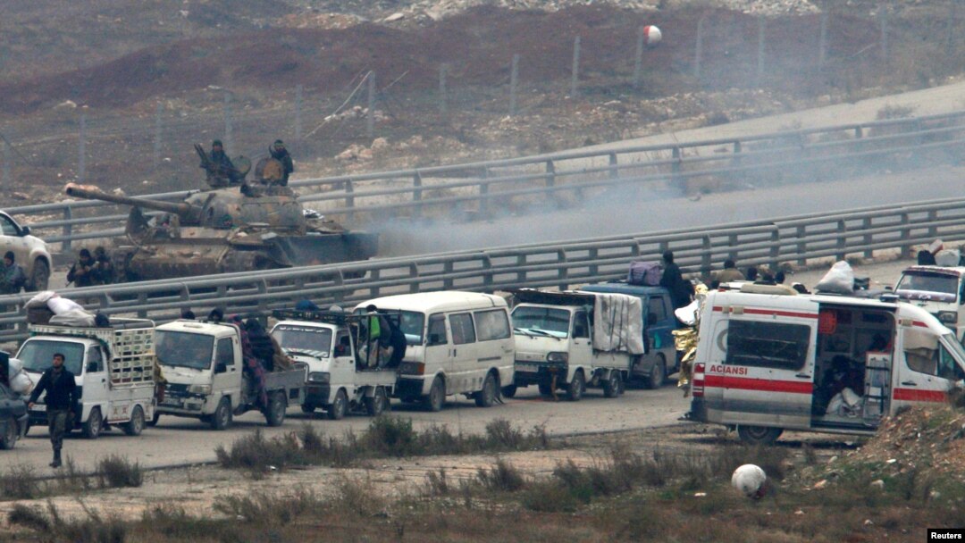 Lực lượng trung thành với Tổng thống Syria ngồi trên xe tăng trong lúc đoàn xe đưa thường dân ra khỏi miền đông Aleppo quay trở lại vùng đất bị bao vây, Syria, 16/12/2016.