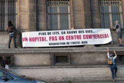 FILE - Activists install a banner reading "More beds can save lives, a hospital not a commercial center, requisition of the Hotel Dieu" to protest against a project next to Notre Dame Cathedral in Paris, April 21, 2020.