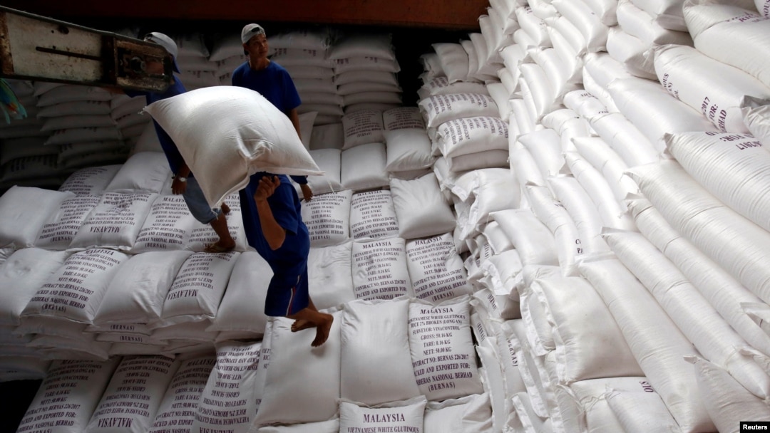 Para pria memuat karung beras ke kapal di sebuah pabrik pengolahan beras di Delta Mekong selatan Vietnam untuk diekspor, Vietnam, 6 Juli 2017. (Foto: REUTERS/Kham)