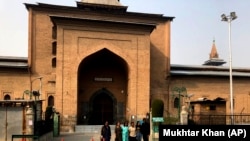 Turis India berfoto di luar Masjid Jamia yang terkunci, atau masjid agung di Srinagar, Kashmir yang dikuasai India, 13 November 2021. (Foto: AP/Mukhtar Khan)