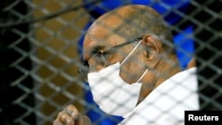 FILE - Sudan's ousted President Omar al-Bashir is seen inside the defendant's cage during his and some of his former allies' trial over the 1989 military coup that brought him to power in 1989, at a courthouse in Khartoum, Sudan, Sept. 15, 2020.