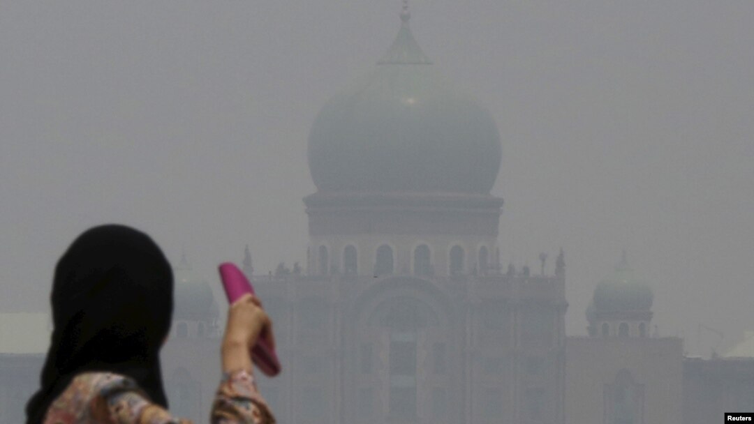 A woman looks toward the prime minister's office, which is shrouded in haze from Indonesian fires, in Putrajaya, Malaysia, Oct. 6, 2015. 