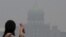 A woman looks toward the prime minister's office, which is shrouded in haze from Indonesian fires, in Putrajaya, Malaysia, Oct. 6, 2015. 