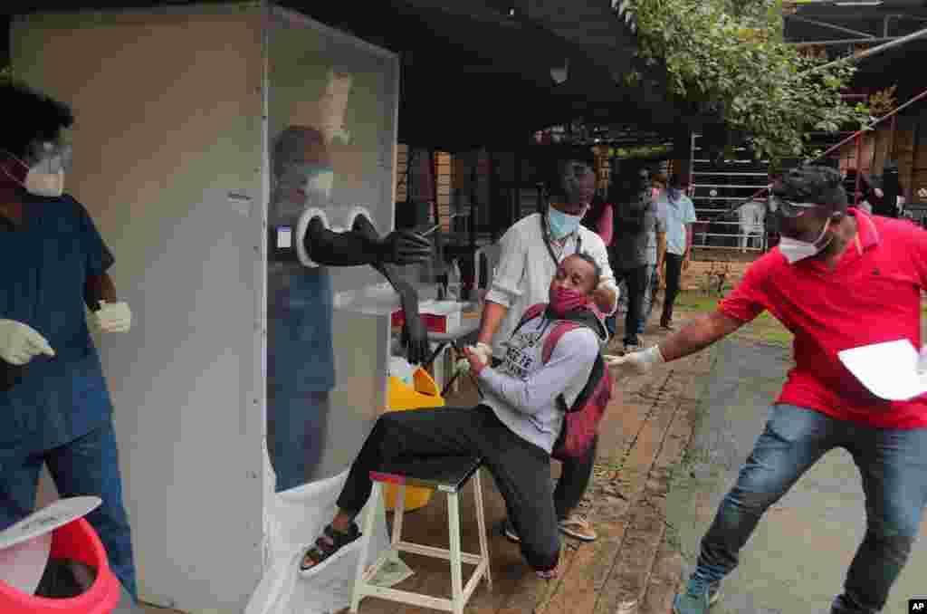 A man reacts as health workers help collect a nasal swab sample to test for COVID-19 in Hyderabad, India.